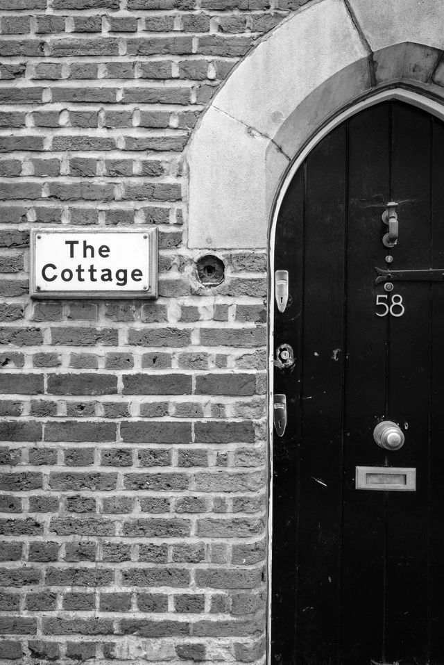 An old door in a brick wall of a building called "The Cottage".