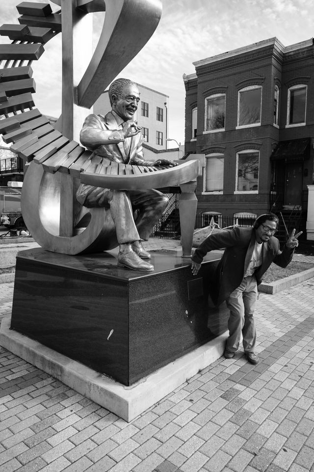 A man giving a V sign at the statue of Duke Ellington in Washington, DC.