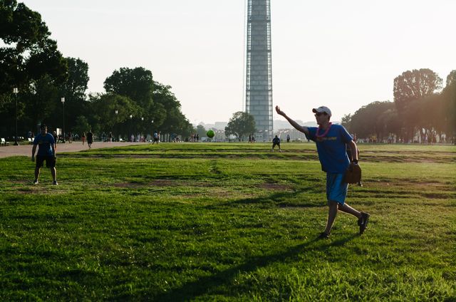 A man playing softball on the National Mall at sunset.