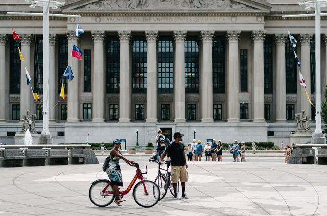 Tourists on bikes at the United States Navy Memorial in Washington, DC, with the United States National Archives in the background.