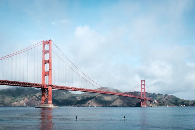 The Golden Gate Bridge, with two surfers paddling in front of it.