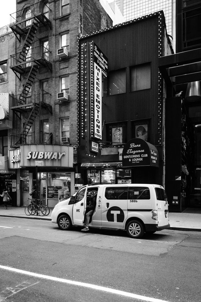 A man getting out of a taxi in front of an adult store in New York City.