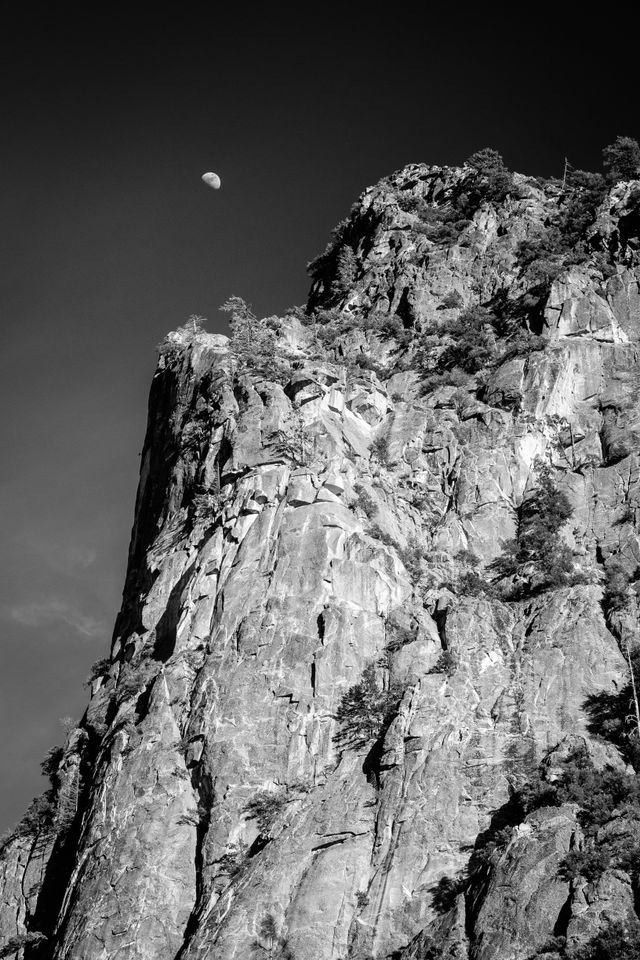 The Moon rising above a rocky cliff in Yosemite National Park.