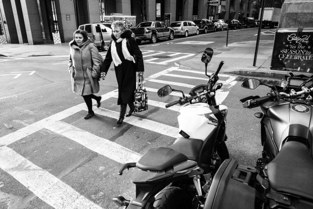 Two women crossing the street near Wall Street.