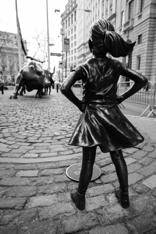 The "Fearless Girl" sculpture in front of the Wall Street Charging Bull.