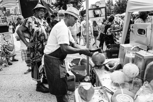 A street vendor cracking open a coconut with an axe at the H Street Festival in Washington, DC.