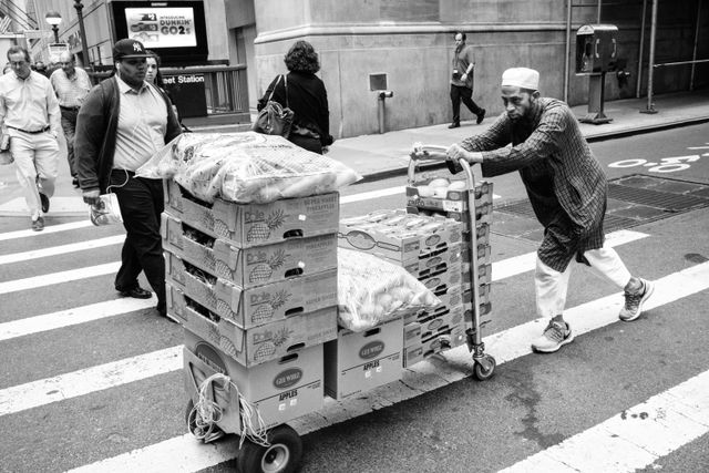 A man pushing a cart full of fruits and vegetables on William Street in New York's Financial District.