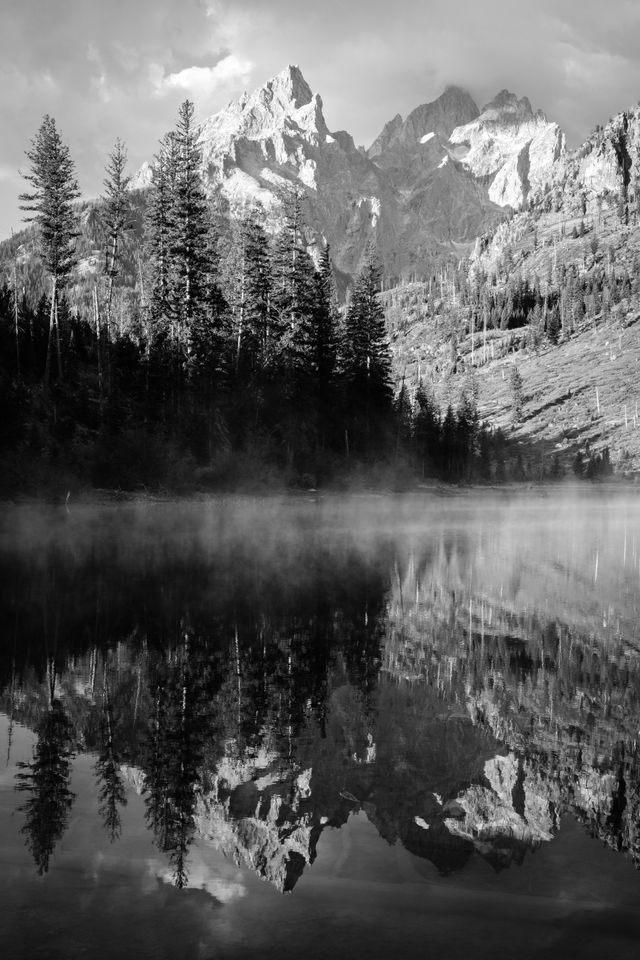 Teewinot Mountain, Grand Teton, and Mount Owen, reflected off the mist-covered surface of String Lake.