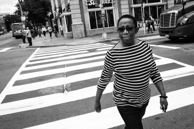 A woman in a striped shirt walking on a crosswalk on 14th & U in Washington, DC.