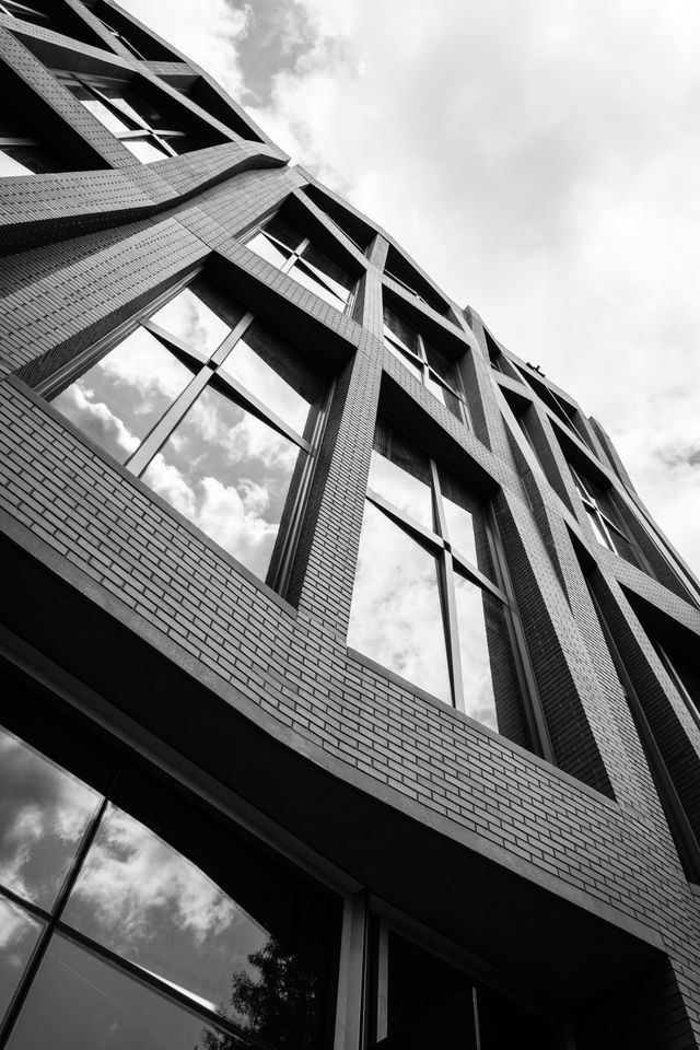 Looking up at the brick facade of the new buildings on Eastern Market, with the sky and clouds reflected off the window panes.