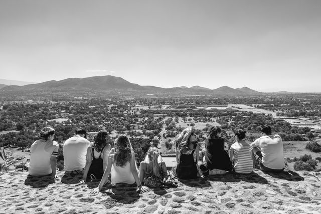 A group of tourists sitting at the edge of the Pyramid of the Sun in Teotihuacán.