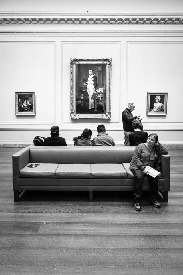 People sitting on a couch in front of a portrait of Napoleon at the National Gallery of Art.