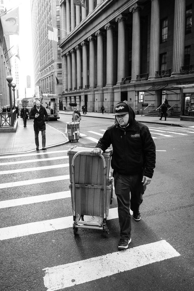 A man pulling a cart on Wall Street, New York.