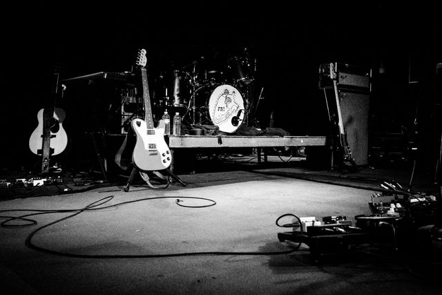 A couple guitars and a drumset on an empty stage ready for a Frightened Rabbit concert.