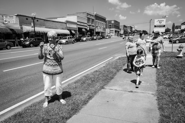 A woman trying on solar eclipse glasses on a sidewalk in Etowah, Tennessee.