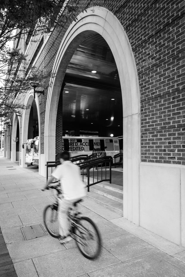 A kid riding a bike past a parking garage in Chattanooga.