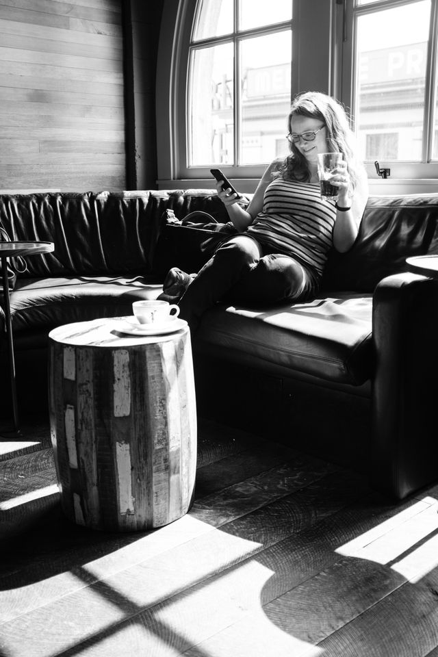 Kate, enjoying some cold brew while looking at her phone at Storyville Coffee Company in Seattle.