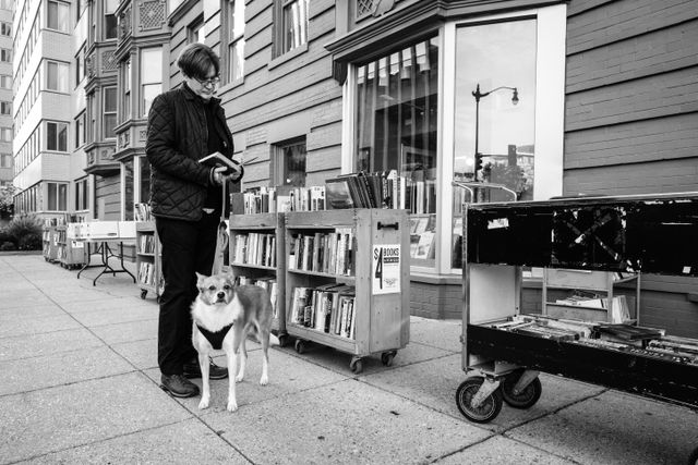 A man and his dog, looking at books at an outdoor stand near Second Story Books near Dupont Circle.