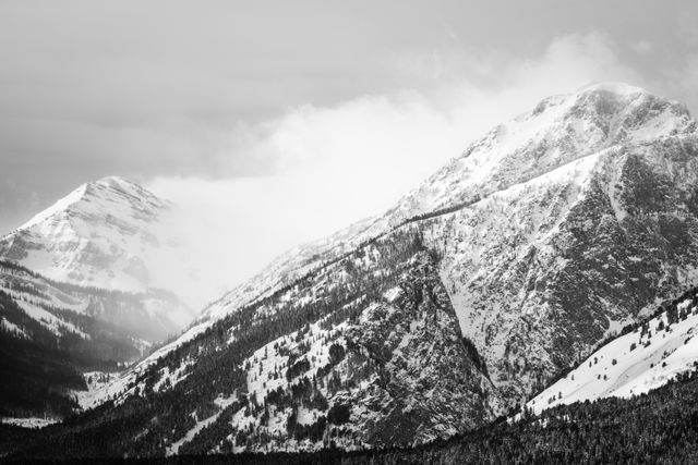 Snow-covered mountains in the Tetons, with clouds rolling by.