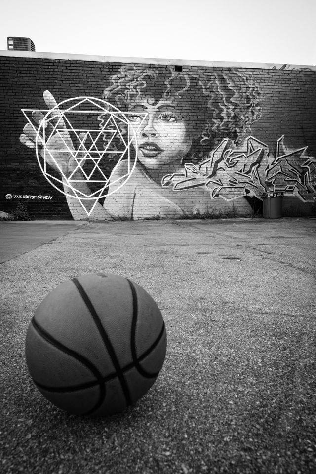 A basketball on a court with a graffiti in the background, in Southside Chattanooga.