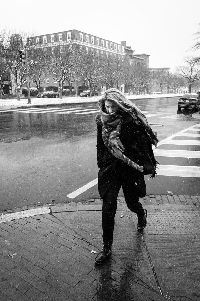 A woman grimaces while crossing the street in the snow, in Capitol Hill.