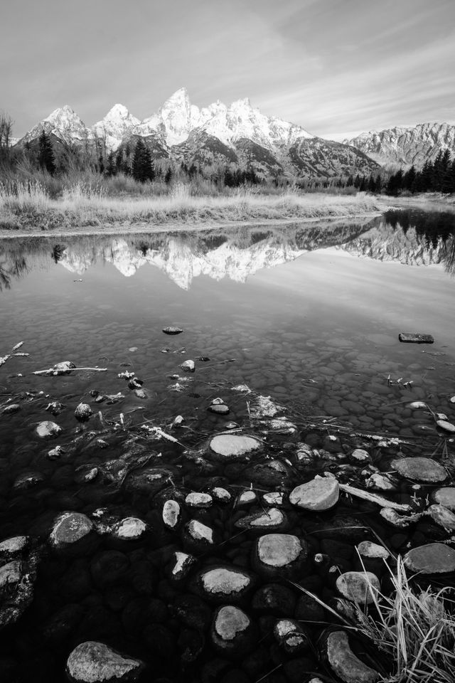 The Teton Range, seen from Schwabacher Landing. In the foreground, rocks near the bank of the Snake River.