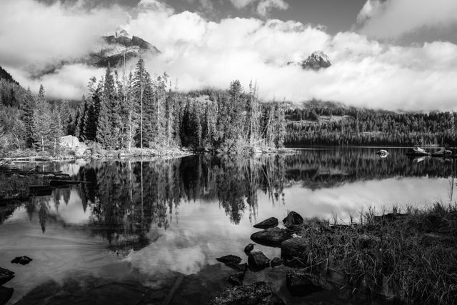 Rocks and grasses on the shore of Taggart Lake. In the background, Nez Perce Peak and Teewinot Mountain poking out from the clouds.