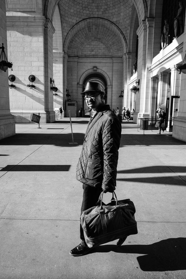 A man wearing a coat and a hat, exiting Union Station in Washington, DC.