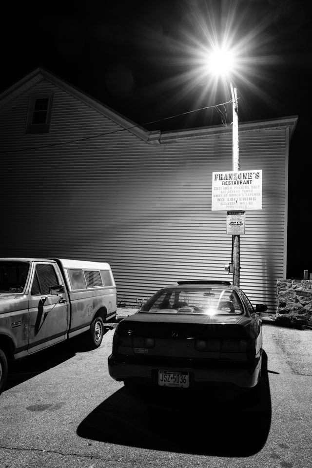 A car parked in front of a hand-painted Franzone's sign in Bridgeport, Pennsylvania.