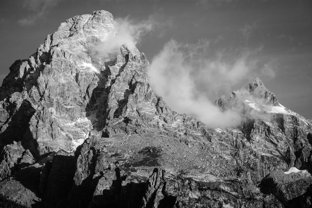 Grand Teton and Mount Owen, with a fresh coat of snow in early fall. Wispy clouds hang in between the two mountains, and in front of the Grand.