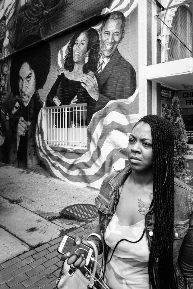 A woman walking past a mural of President Obama, Michelle Obama, and Prince, on U street.