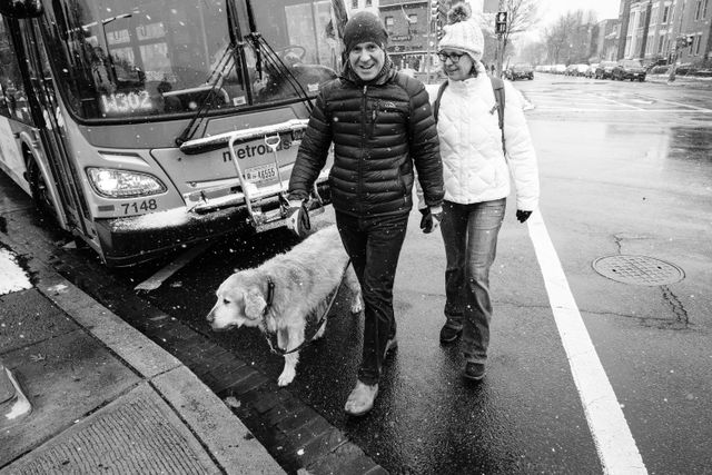 A couple walking a cute golden retriever on a snowy day in Capitol Hill.