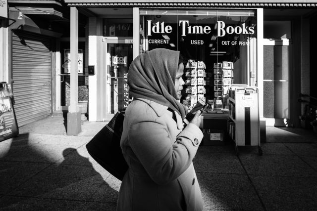 A woman talking on the phone while walking in front of Idle Time Books in Adams Morgan.