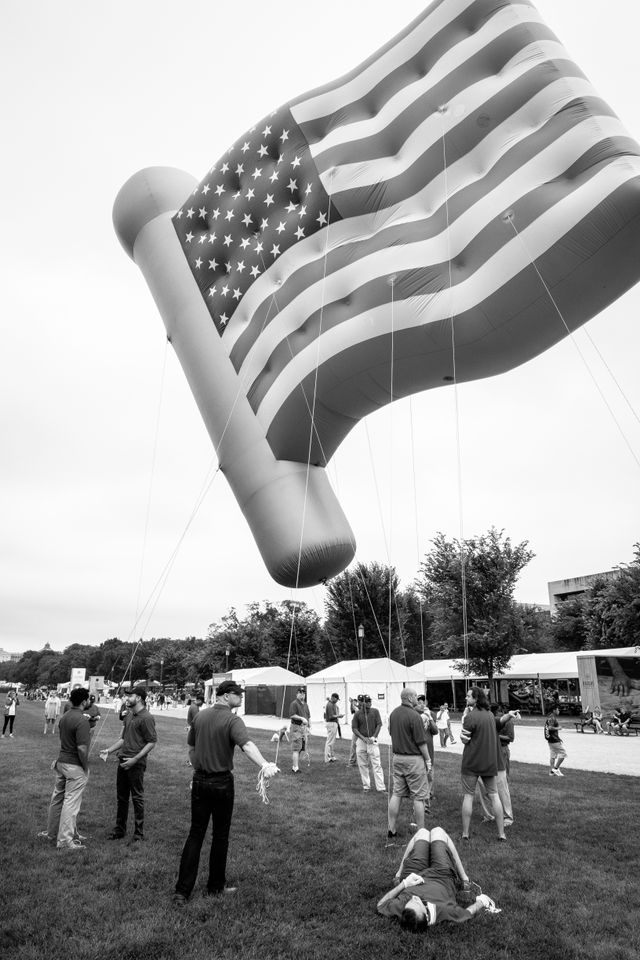 A group of people holding on to a giant inflatable American flag.