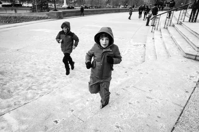 Two kids running on the west front of the United States Capitol building.