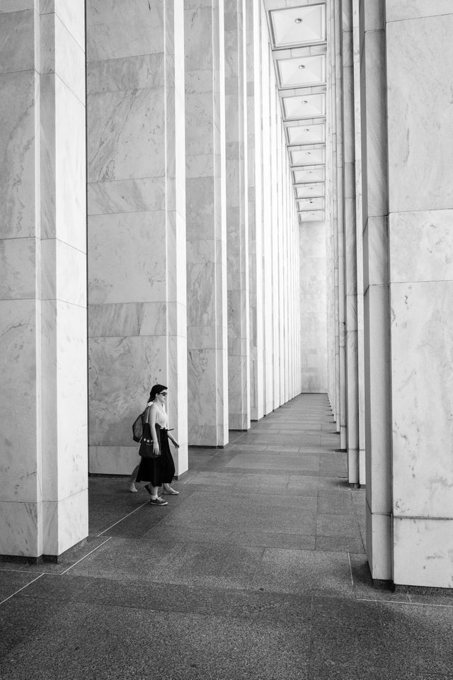 Two people walking past the columns of the Madison building of the Library of Congress.