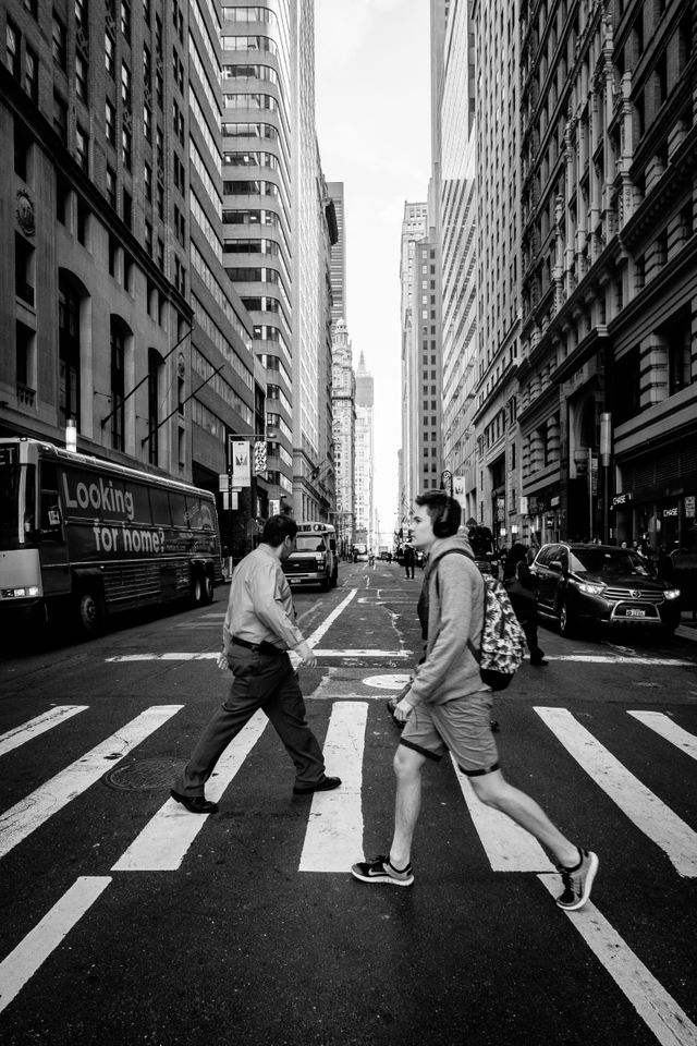 Two pedestrians on a crosswalk on Broadway.