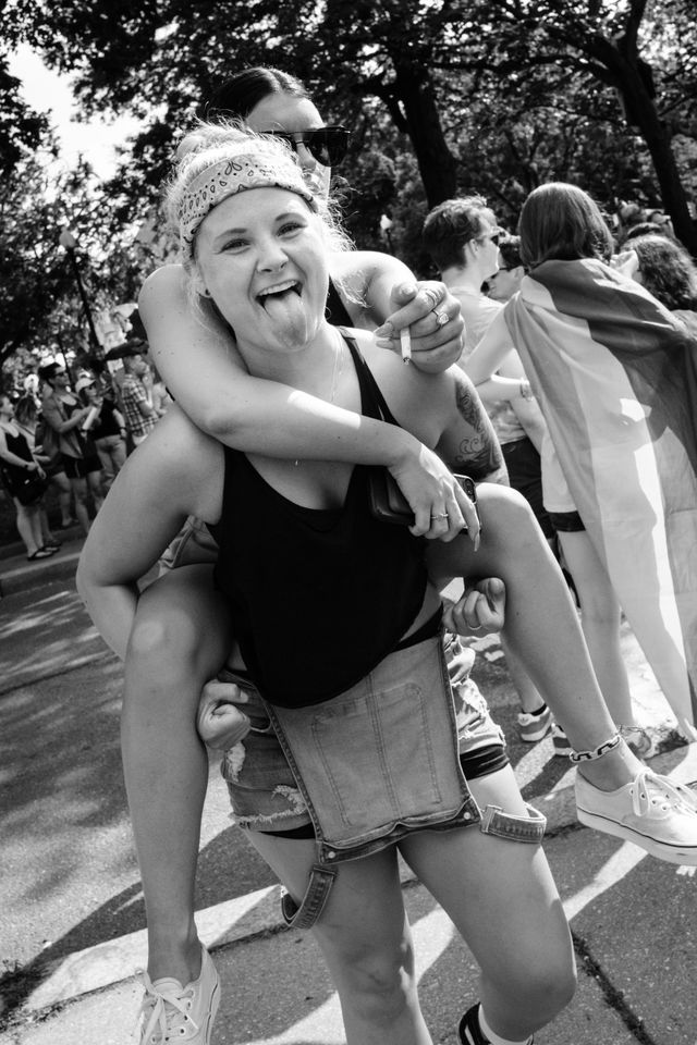 A person sticking out their tongue while carrying another person on piggyback at the Capital Pride Parade.