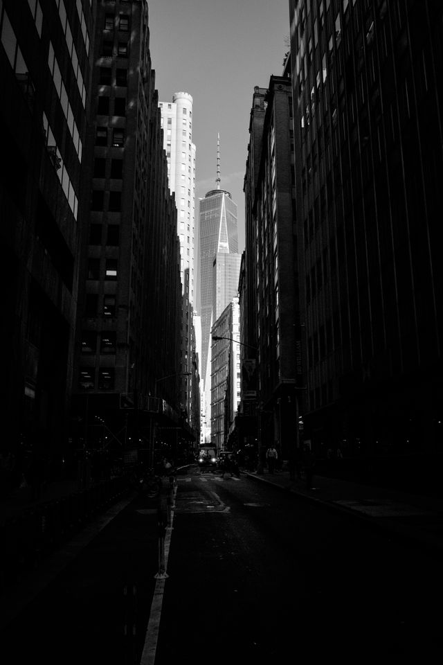 One World Trade Center, framed by buildings along John Street in the Financial District of New York.