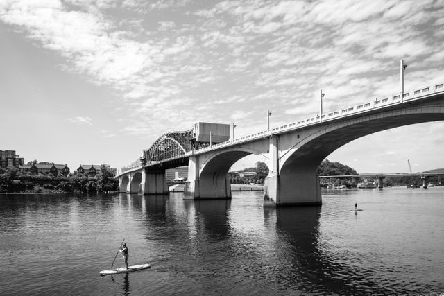 People on paddle boards on the Tennessee river in Chattanooga, with the John Ross Bridge in the background.