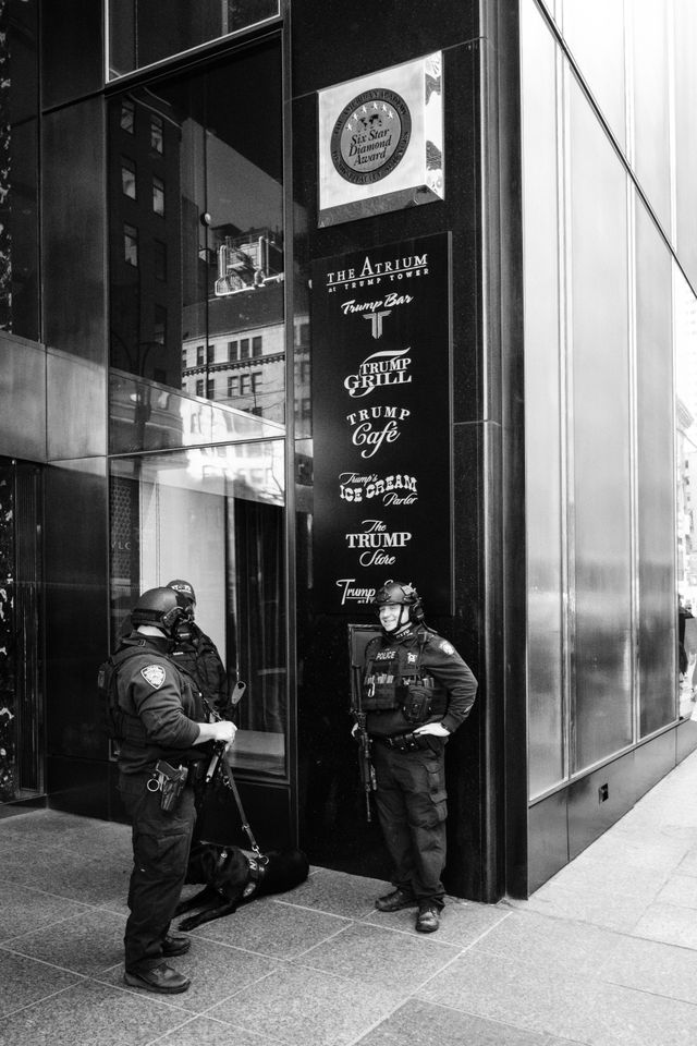 Three NYPD officers and a dog standing outside Trump Tower in New York City