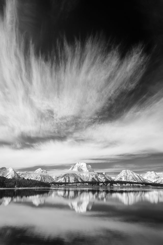 Mount Moran and its reflection on Jackson Lake, with wispy clouds overhead.