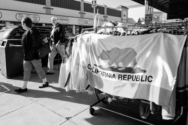 Two tourists walk past a California flag at a store in Fisherman's Wharf, San Francisco.