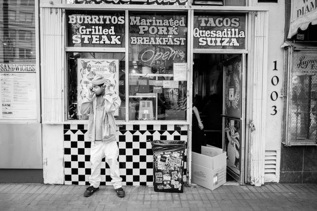 A man talking on a cellphone in front of a Mexican food restaurant on Market Street.