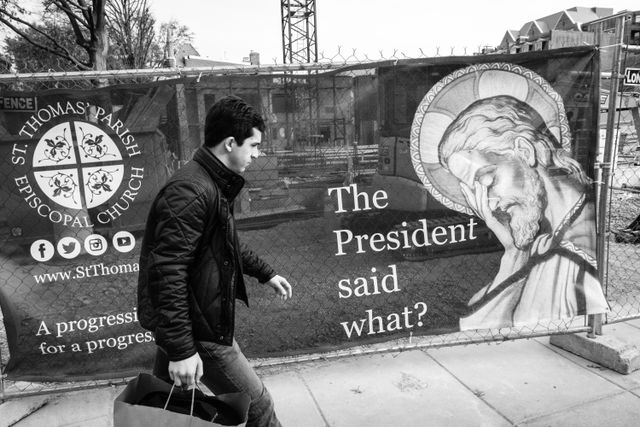 A man walking in front of a church sign that shows Jesus facepalming and asking "the president said what?"