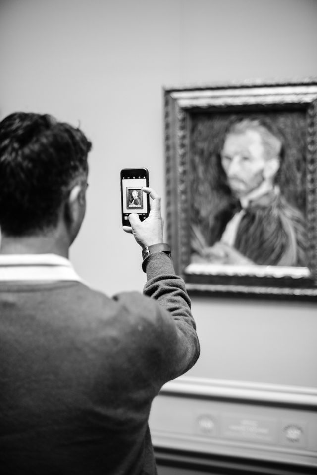 A person taking a photo of a self-portrait of Vincent van Gogh at the National Gallery of Art.