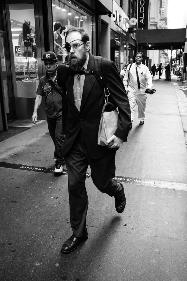 A man wearing an eyepatch waking down Broadway in the Financial District.