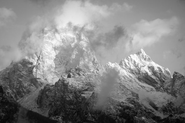 Grand Teton and Mount Owen, covered in the first big snowfall of the fall, at sunrise, with clouds hanging around them.