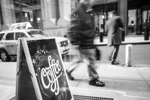 People walking by a coffee sign at the Black Fox coffee shop in New York's Financial District.