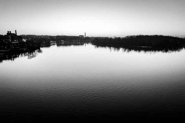 The skyline of Washington, DC, including Georgetown to the left, the Washington Monument in the center, and Roosevelt Island to the right, and the Potomac river in the foreground, from the Key Bridge, at dawn.